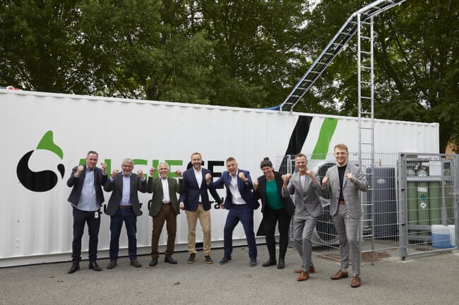 um grupo de homens comemorando em frente a um contêiner de transporte