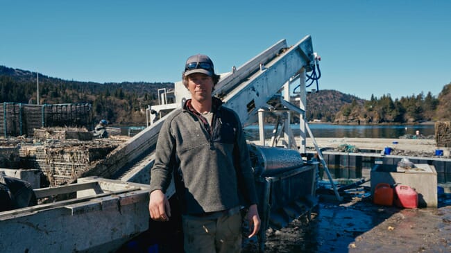 A man standing beside machinery on a raft.