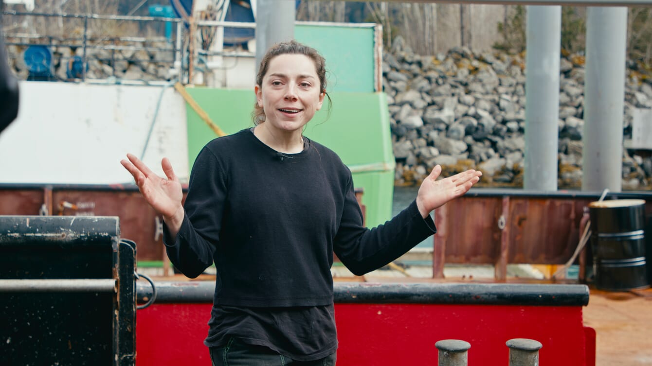 A woman holding her hands aloft on a dock.