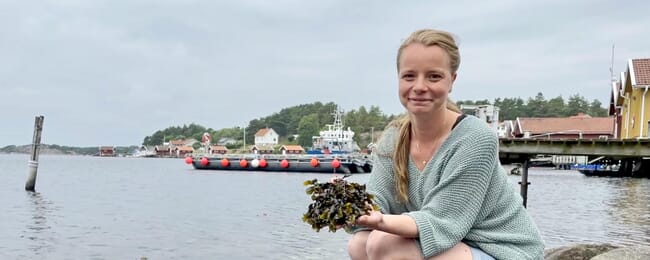 a lady on a pier holding a piece of seaweed