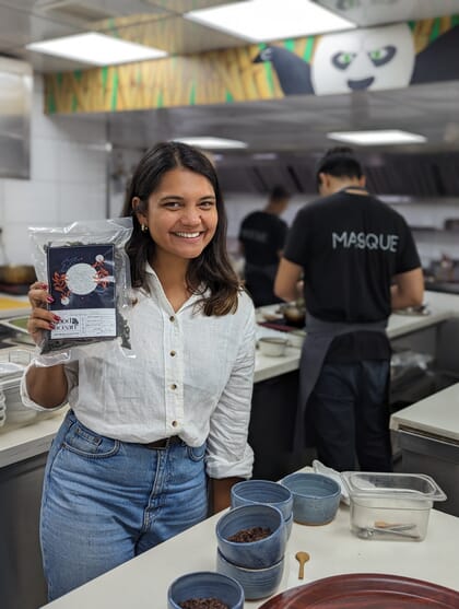 A woman in a commercial kitchen holding up a bag.