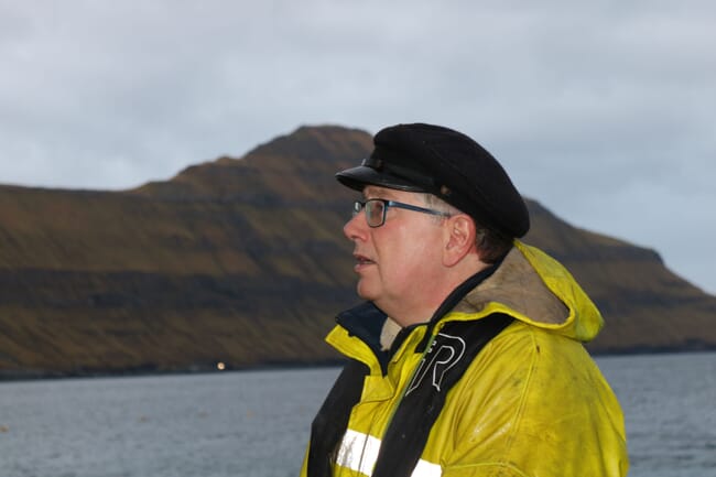 a man standing on a boat with mountains in the background