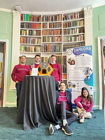 A group photo around a small promotional stand.