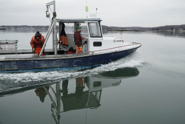 two people standing on a boat that's heading out to sea