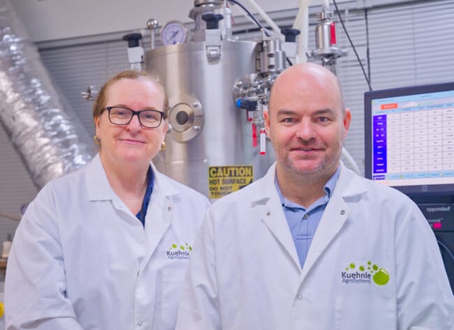 Duas pessoas vestindo jalecos, em um laboratório.