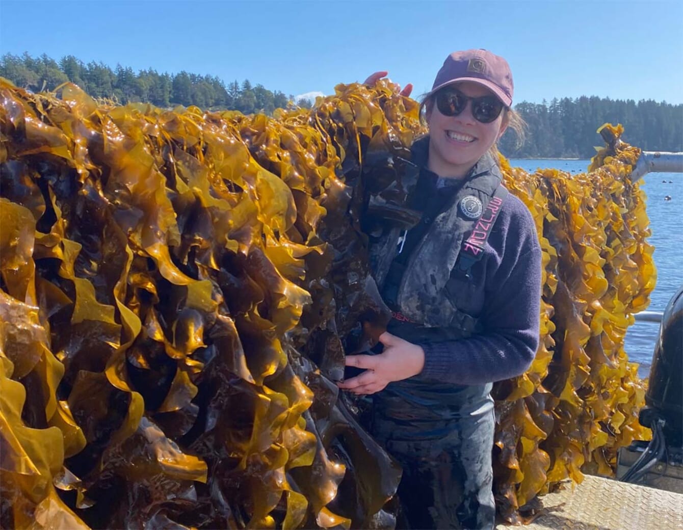 A woman standing beside a line of rope-gown seaweed.