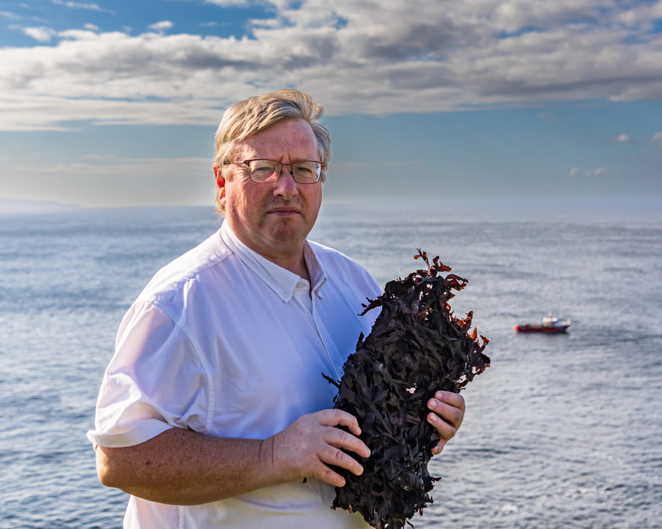 um homem segurando um tufo de algas marinhas