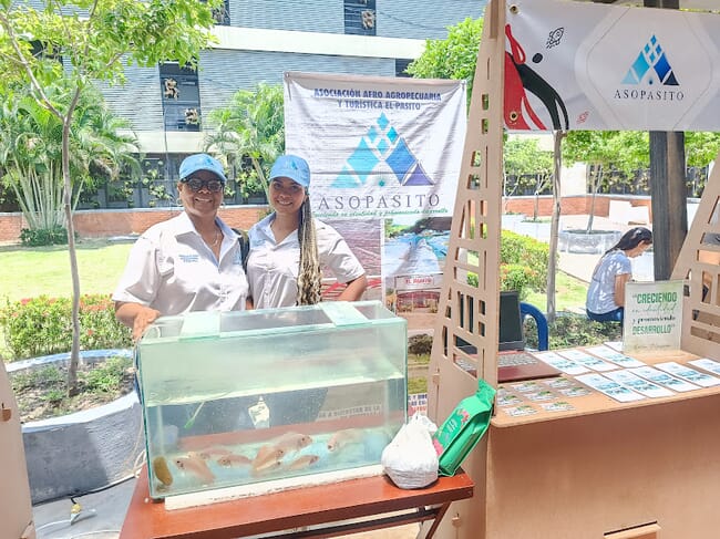 Two women standing behind a small fish tank.