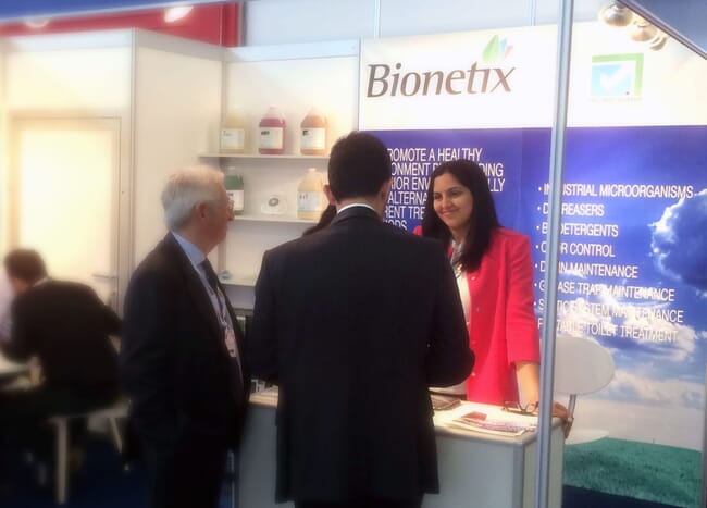 A woman standing with two men at a trade show.