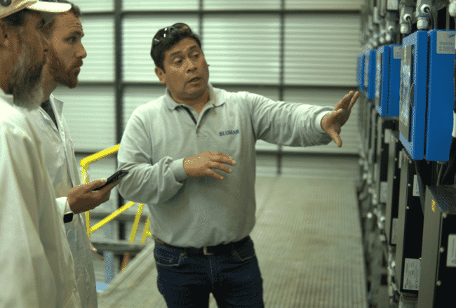 A man explaining how hatchery equipment works to two visitors