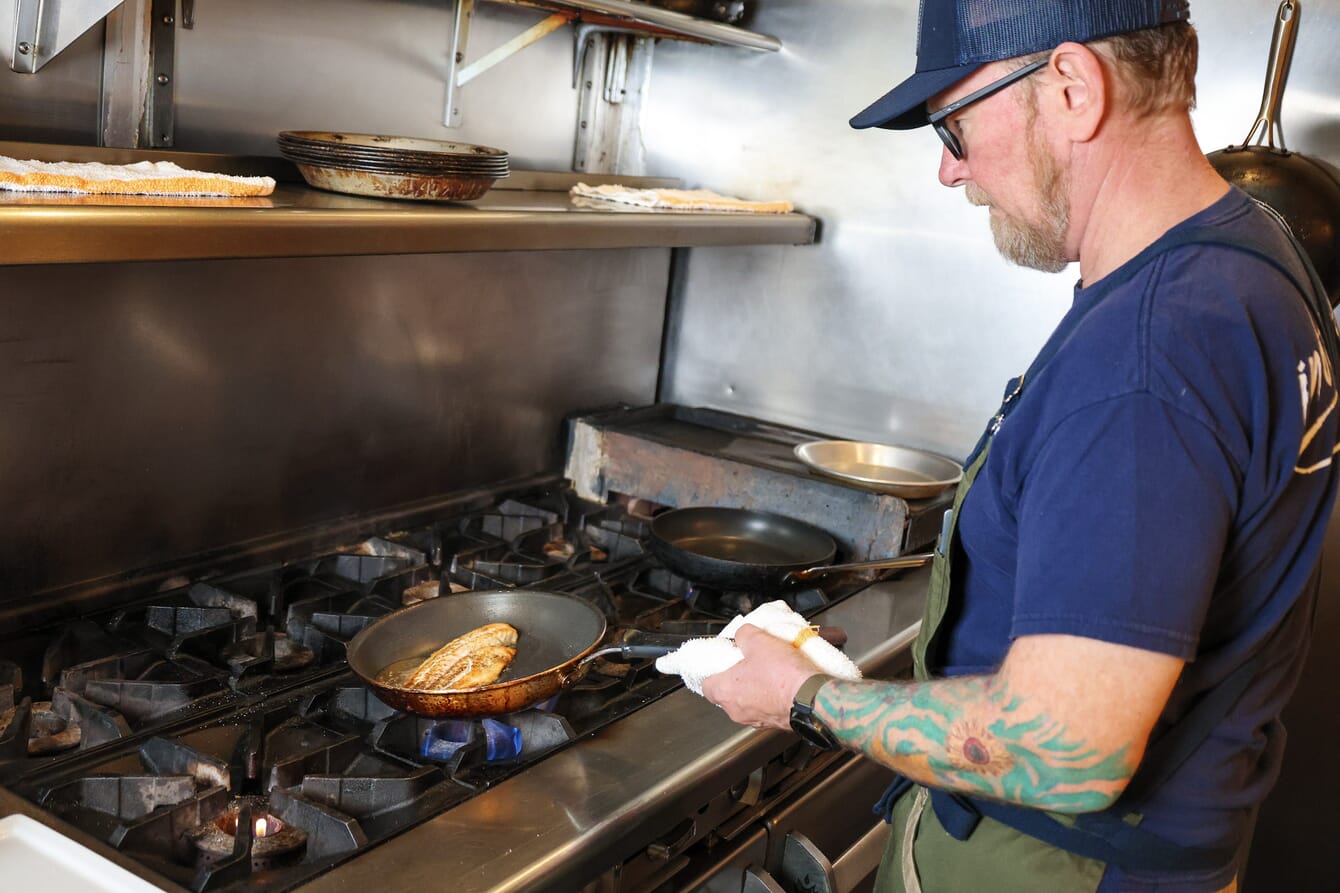 A chef cooking fish from aquaculture in a pan in Florida.
