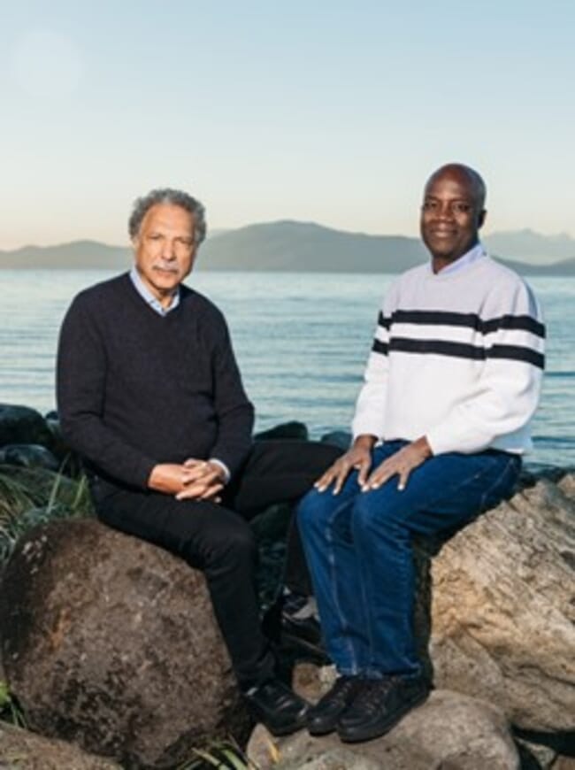 two men sitting on the seashore