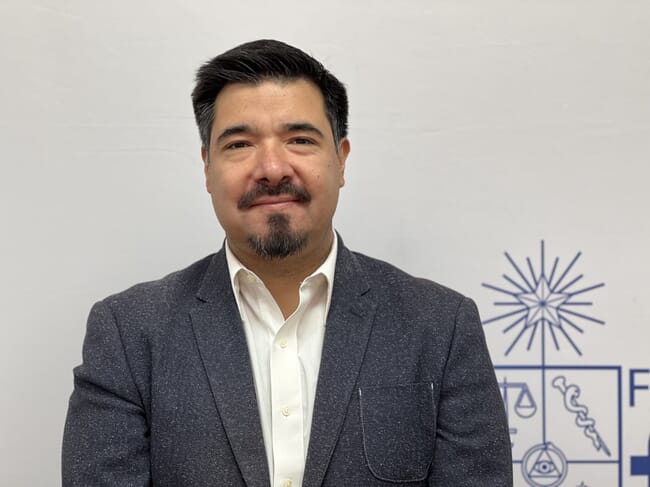 A headshot of a dean of a university in a suit.