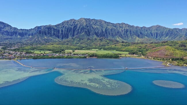 A fish pond with large mountains in the background.