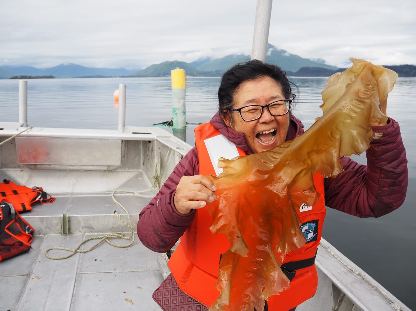 A person holding a frond of seaweed.