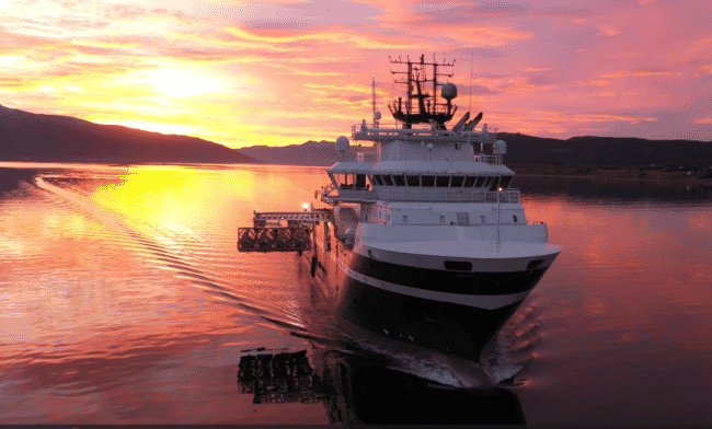 a large vessel at sea with the sunset in the background