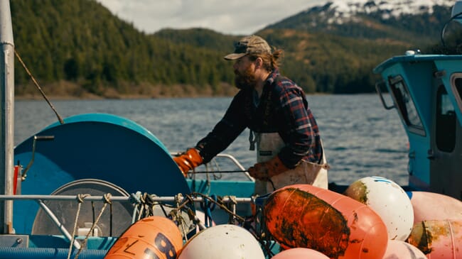 A man standing beside a winch on a boat.