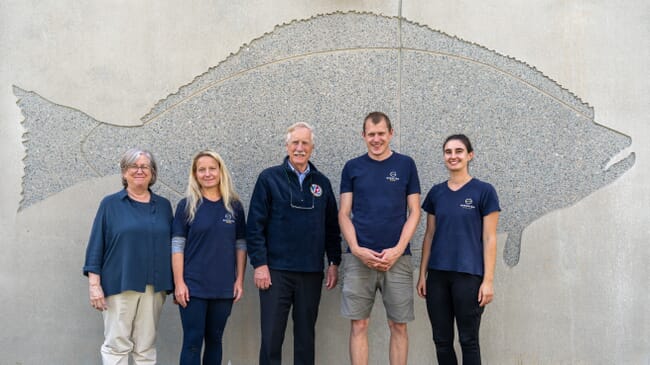 five people standing in front of a grey wall