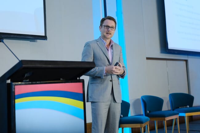 A man in a suit giving a lecture.