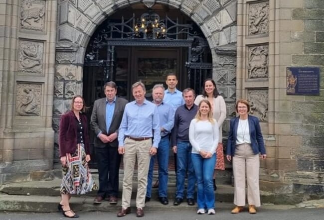 uma foto de grupo do lado de fora da entrada de um edifício histórico de pedra