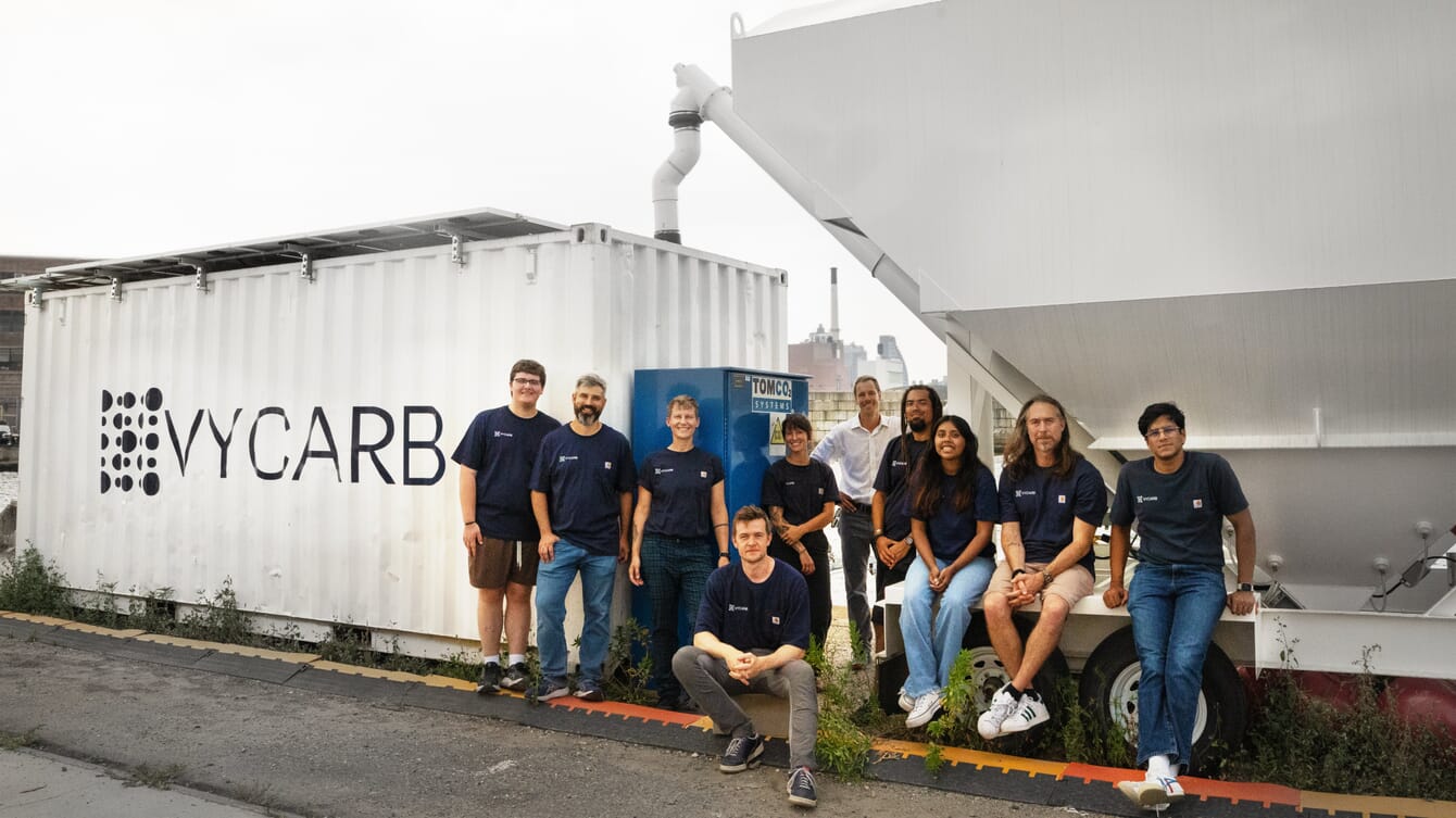 A team posing infront of their modular carbon capture technology in New York City.