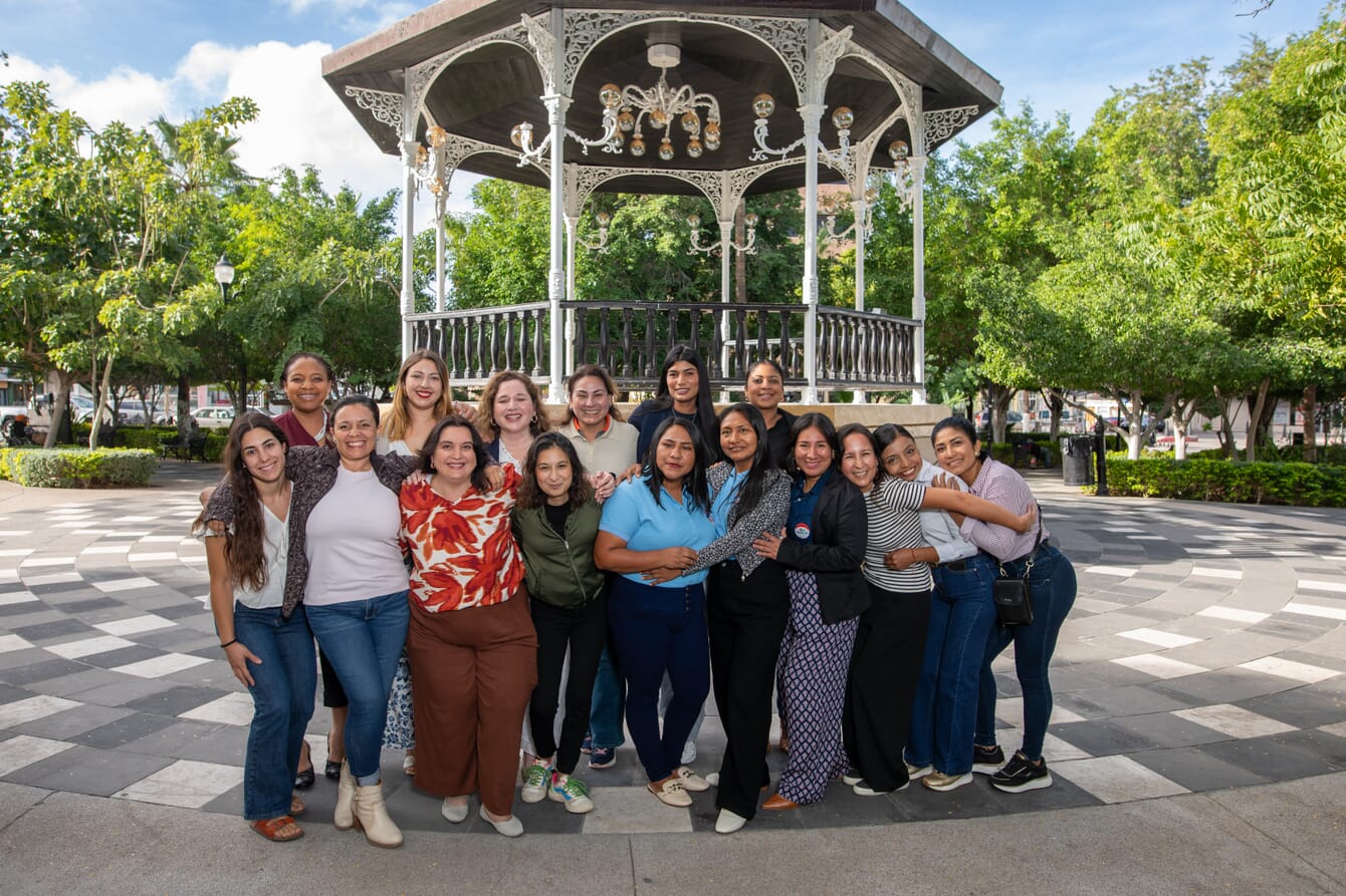A group of women entrepreneurs taking a group photo in a park on a sunny day.