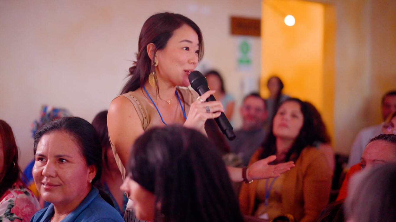 A woman speaking into a microphone at an event.