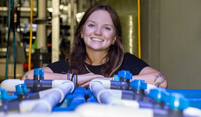 A young woman leaning on some blue pipes.