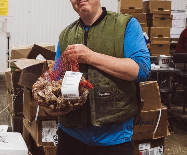 A man holding a net bag of oysters.