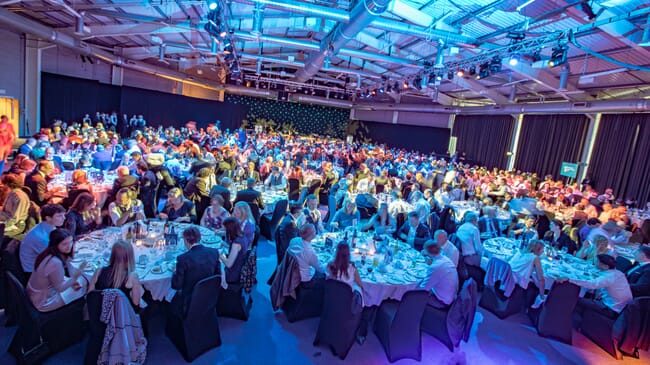 people sitting around tables in a marquee