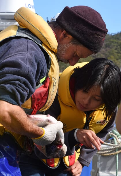 woman examining a fish that's being held by a man