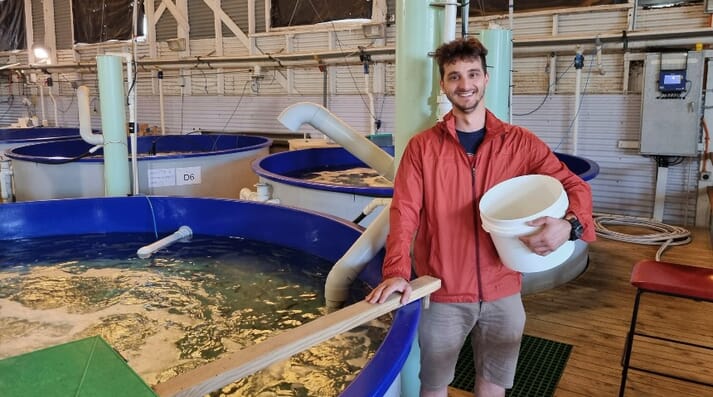 Man in a red jacket standing next to a hatchery tank