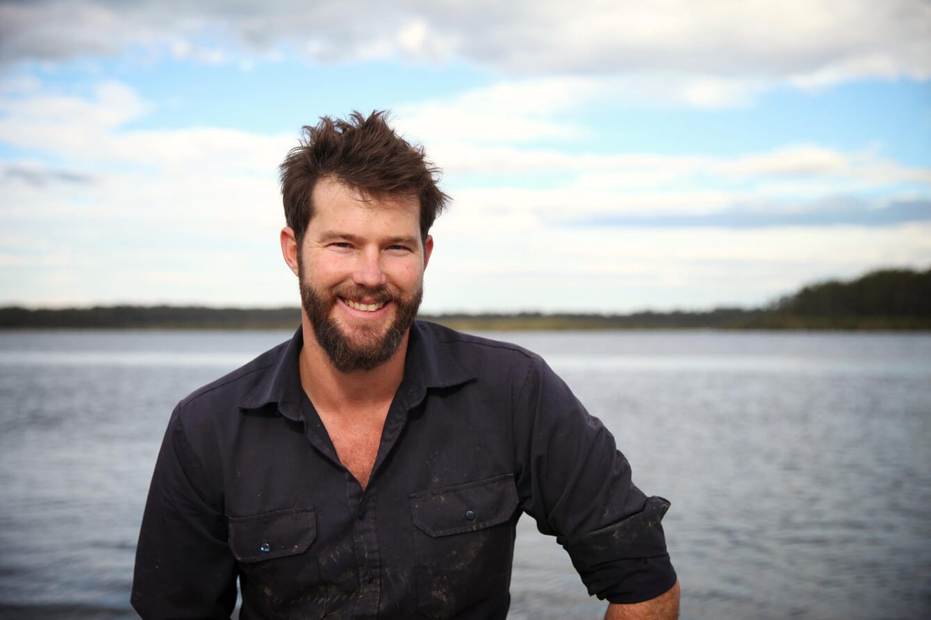 man standing in the sea holding an oyster