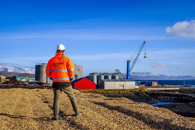 a person in a hi-viz jacket in front of an industrial construction