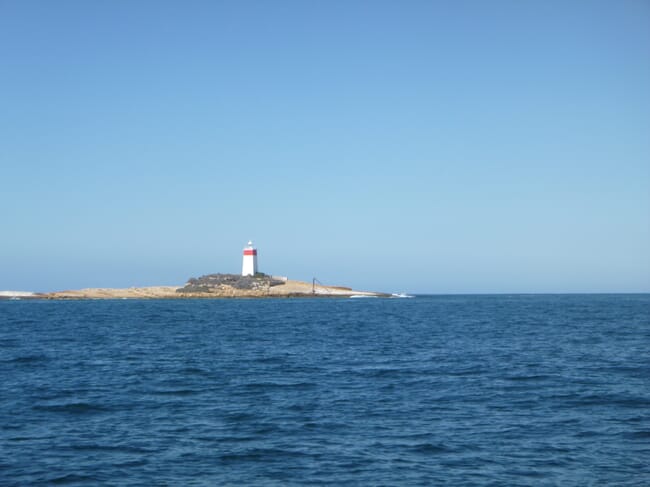 Masa de agua con un faro a lo lejos