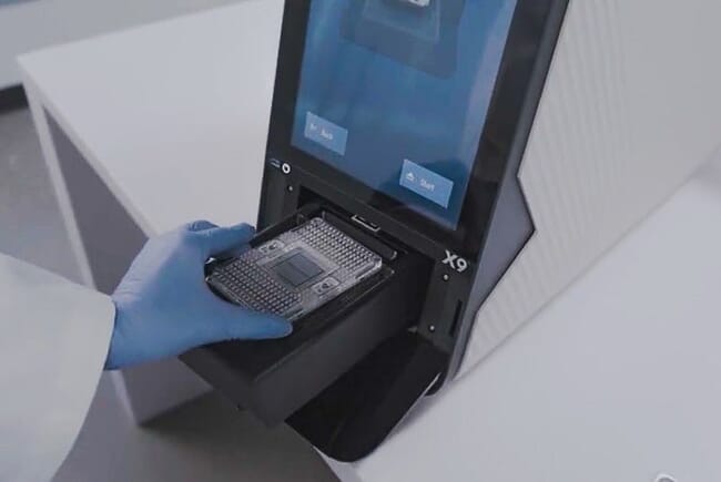 A mão de uma pessoa removendo amostras de uma máquina.