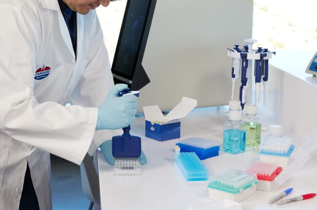 A person holding a pipette in a laboratory.