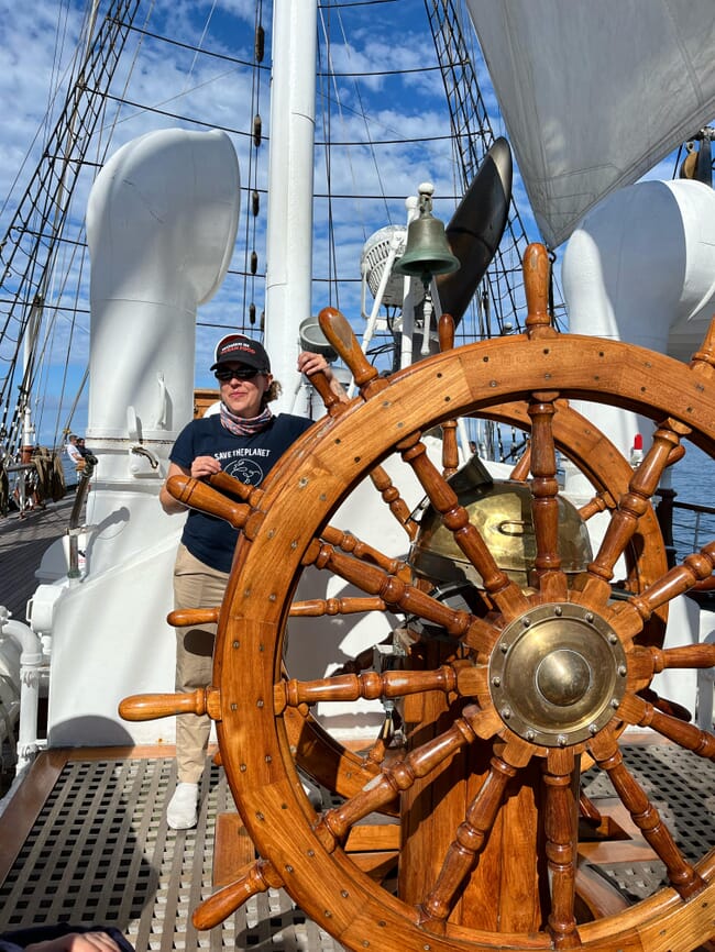 A woman in charge of stiring the Helm of a Norwegian tall ship.