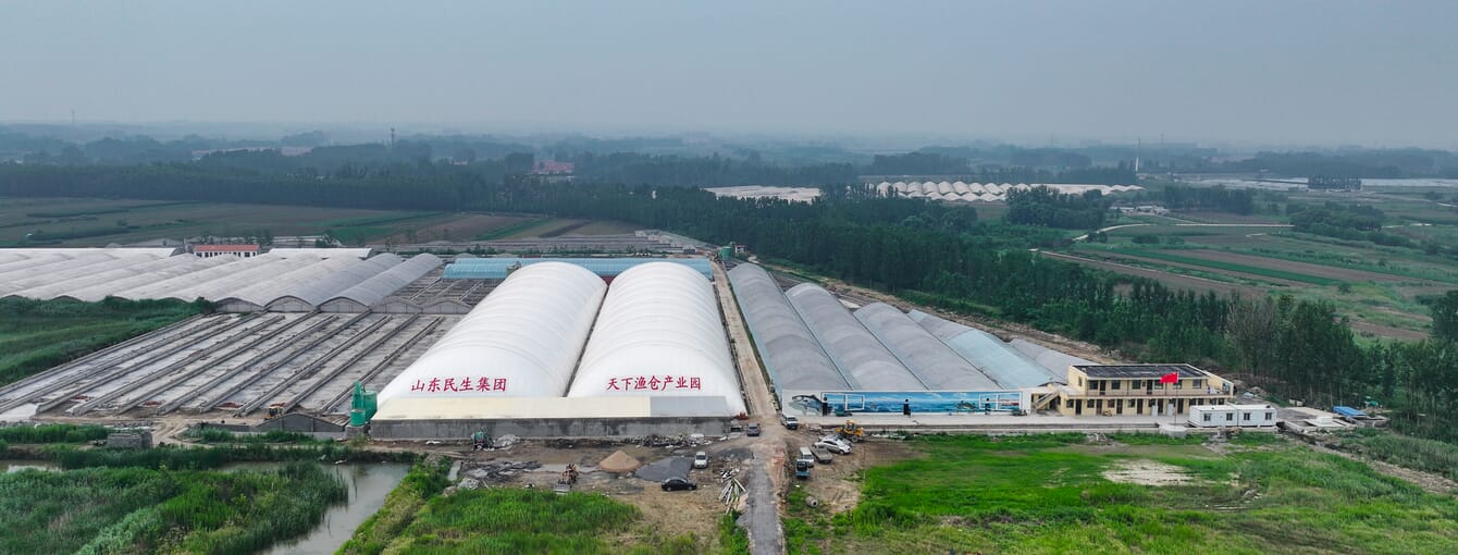 An aerial view of an airdome shrimp farm beside polytunnels