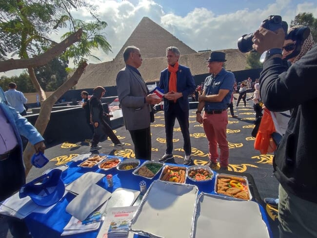 Three men eating seafood in front of the Egyptian pyramids