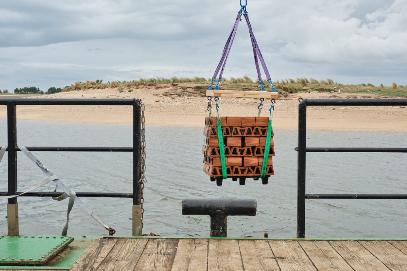 An artificial oyster reef being lowered from a boat into the sea.