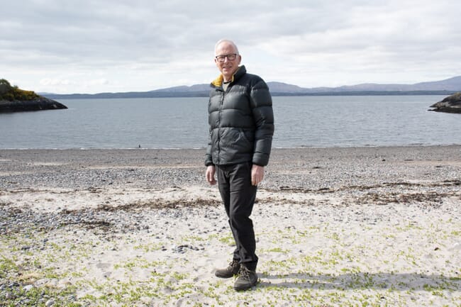 Professor Michael Burrows stands on a beach