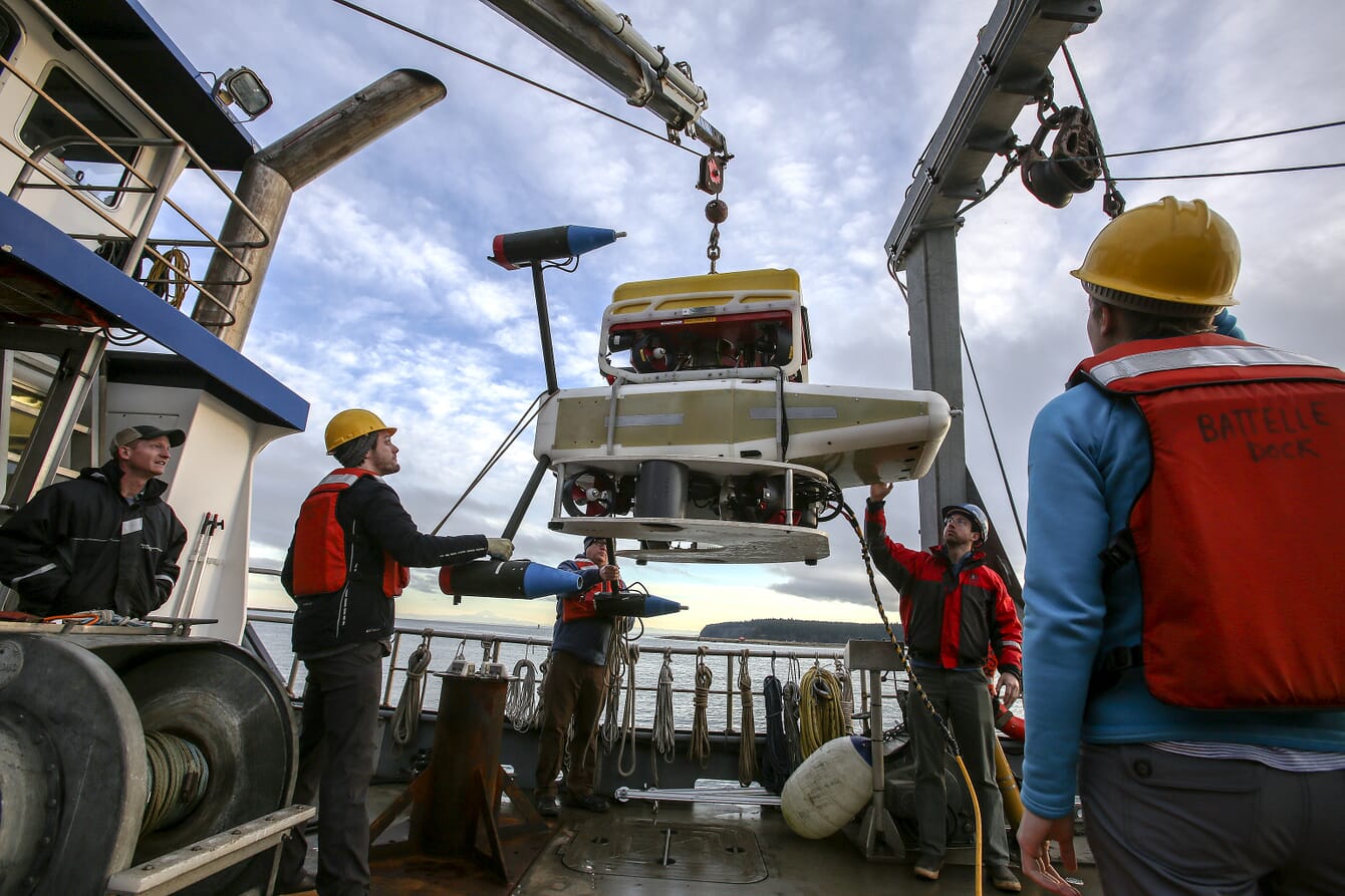 Engenheiros implantando uma matriz de monitoramento marinho a bordo de um barco.