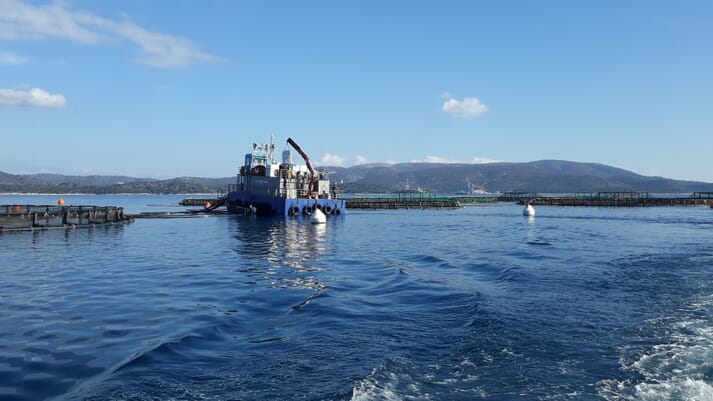 A barge floating next to fish pens