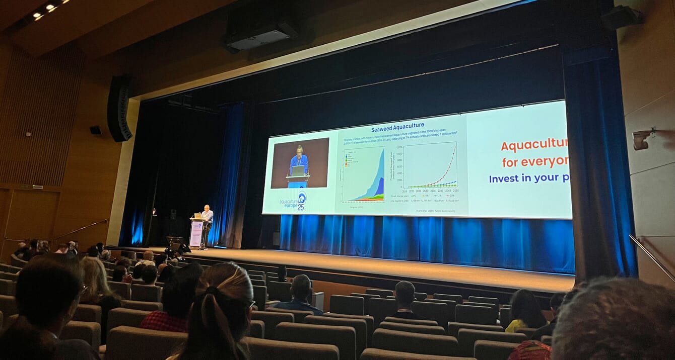 A scientist giving a talk in a large auditorium.