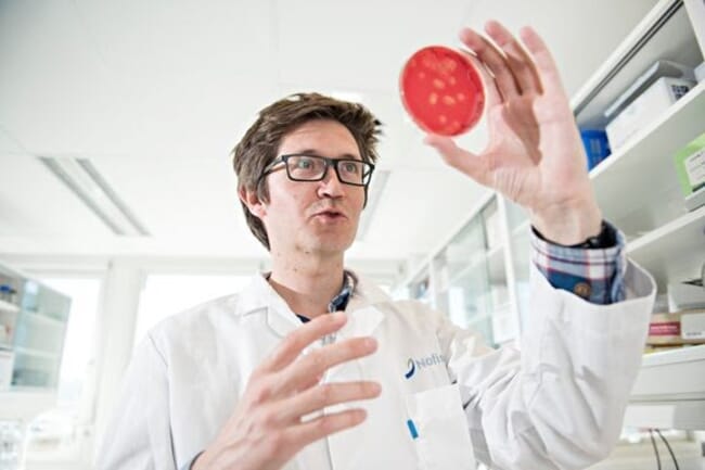 um homem inspecionando uma placa de Petri