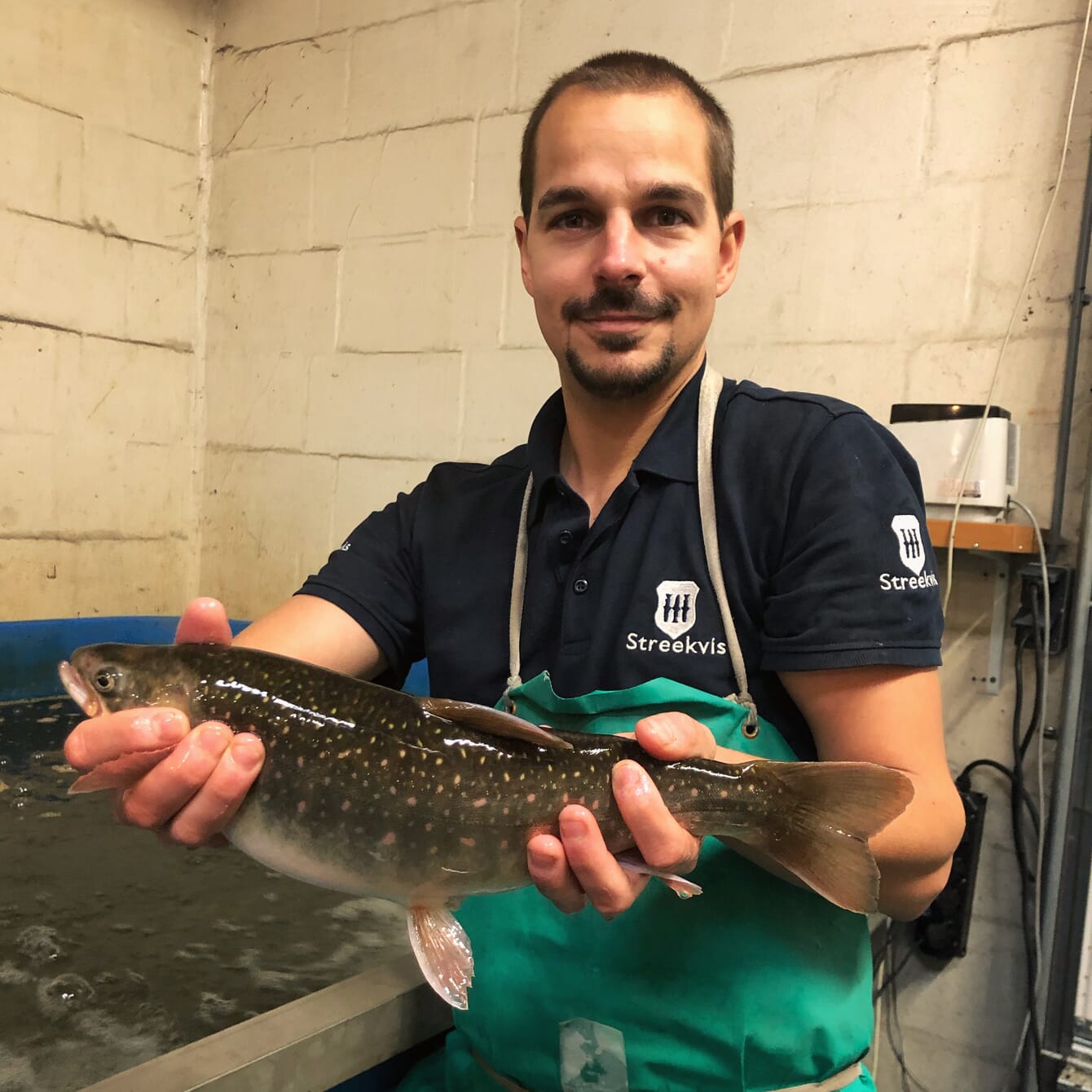 A farmer holding an Arctic char in his hands.