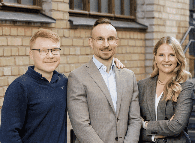 A group of three people in business attire posing for a photo.
