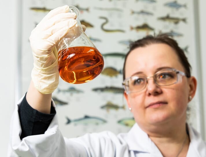 Woman holding a flask of fish oil in a lab