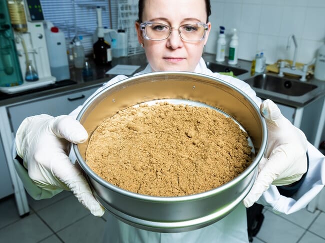 a lady holding a pot of brown powder.